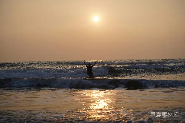 高清摄影 海边举起双臂的人在夕阳下
