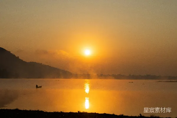 高清摄影 湖面上夕阳西下，一艘小船在水中。