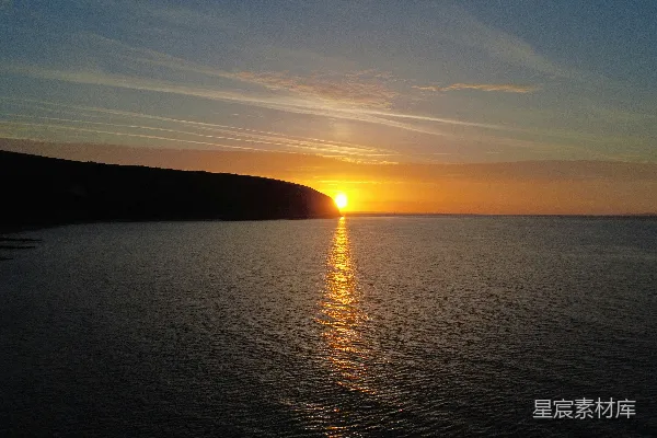 高清摄影 金色的夕阳映照在波澜壮阔的大海之上，海岸线则被染成了深邃的颜色。