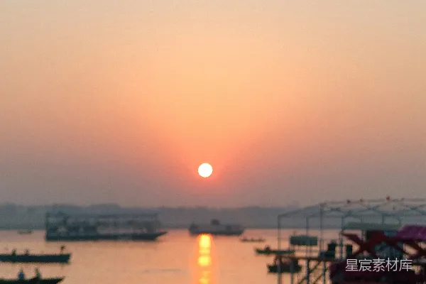 高清摄影 橙色的夕阳映照在一条河上，河上有船只。
