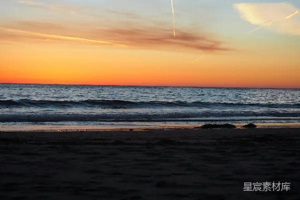 高清摄影 夕阳下的海景，一架飞机在天空中。