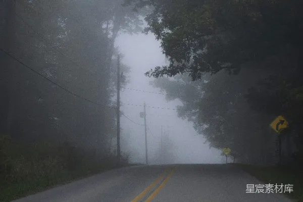 高清摄影 一条雾气弥漫的道路，路边挂着一块黄牌子。
