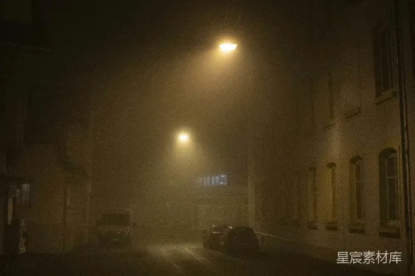 高清摄影 夜晚的一条雾气缭绕的街道，车辆停在路边。