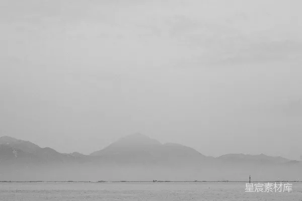 高清摄影 雾蒙蒙的山峦耸立在一片宁静的海面上。