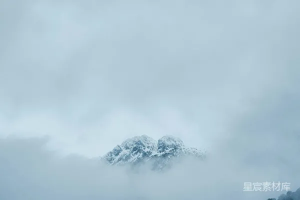 高清摄影 远处有一座被云层覆盖的山峰，山顶积雪皑皑。