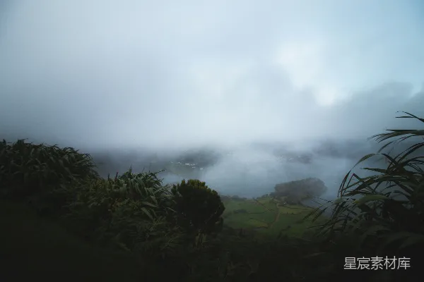 高清摄影 一片烟雾笼罩的山水画，有树木和一处水面。