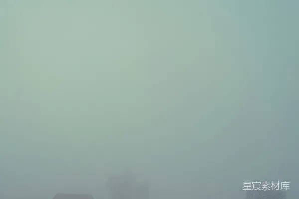 高清摄影 远处有一片雾气笼罩的田野和几棵树木，在远处还有一座谷仓。