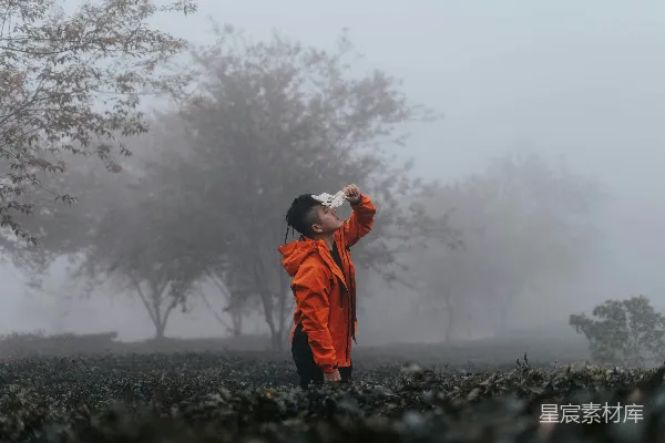 高清摄影 橙色夹克的男人站在黑色的岩石上