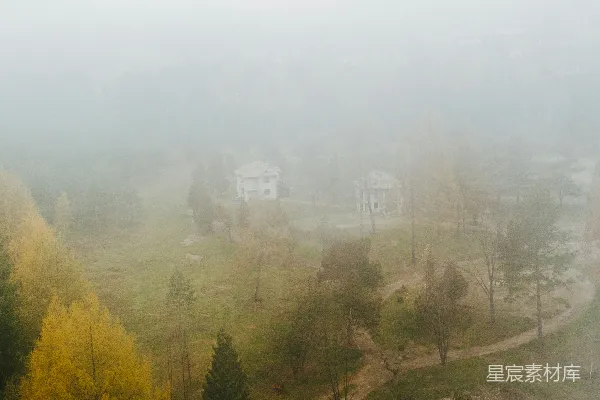 高清摄影 远处有一片雾气笼罩的风景，有树木和房屋。