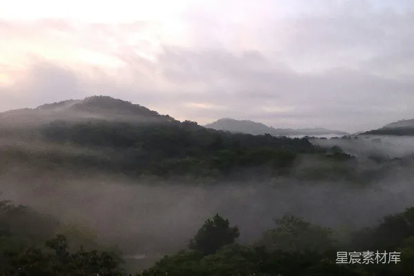 高清摄影 山间有树和丘陵的背景，一片雾气蒙蒙。