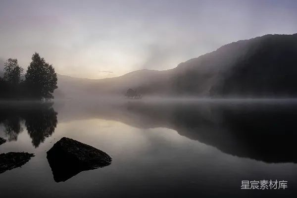 高清摄影 湖边雾气弥漫，背景是树木和山峦。