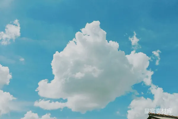 高清摄影 蓝天上漂浮着几朵白云，一座房屋在上方。