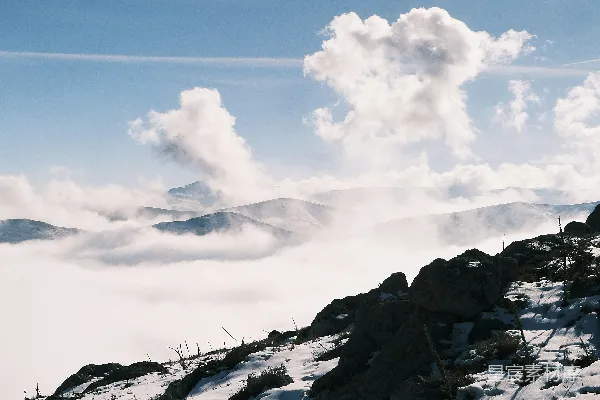 高清摄影 山顶上站着一个男人，他周围是覆盖着白雪的山峦。
