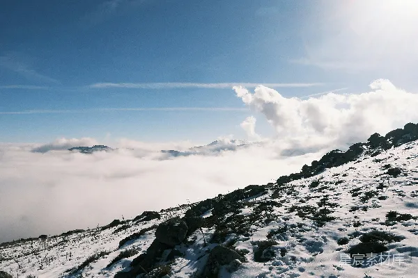 高清摄影 山顶上站立着一个男人，身后是覆盖着白雪的山峦。