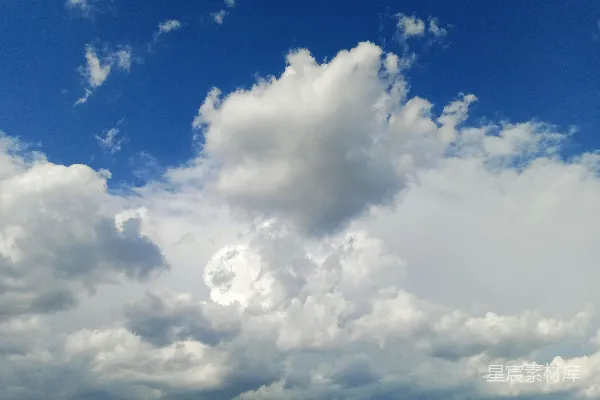 高清摄影 一群人在一片绿油油的草地上站立，周围是多云的蔚蓝色天空。