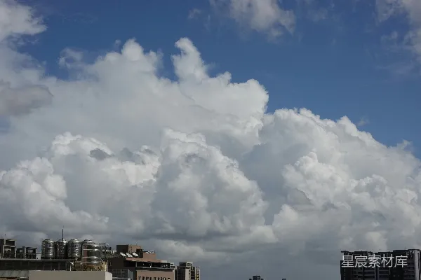 高清摄影 城市建筑上方明亮的蓝色天空中有大片白云。