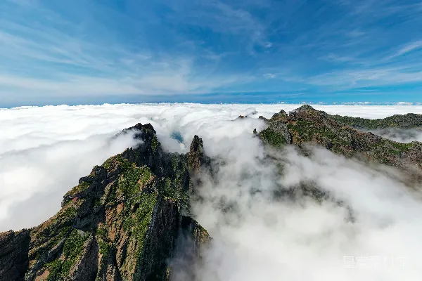 高清摄影 一座被云环绕的高大山脉，镶嵌在蔚蓝的天空下。