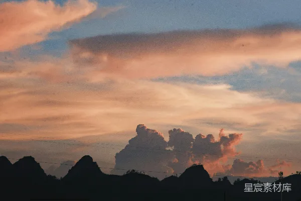 高清摄影 夕阳下， dramatic 粉色云朵映衬着轮廓分明的山峰。