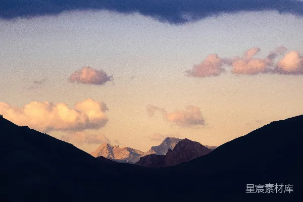 高清摄影 山峰矗立在柔和的天空背景下，云朵环绕其旁。