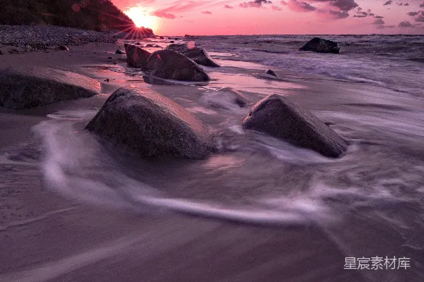 高清摄影 夕阳西下，海平面上有岩石作为前景。