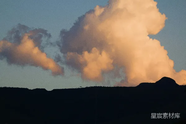 高清摄影 夕阳下的粉红云彩照亮了周围的黑暗山丘。