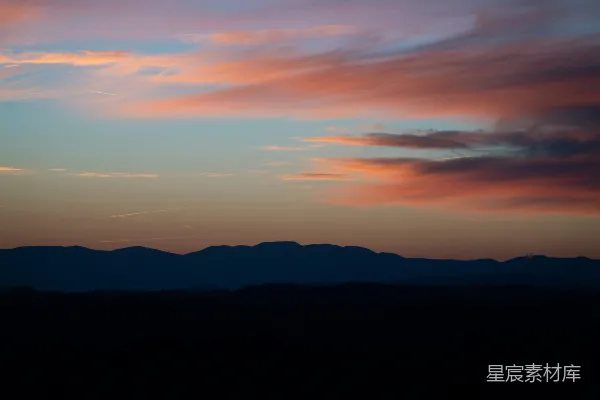 高清摄影 远处山峦上方粉红色和蓝色的夕阳。
