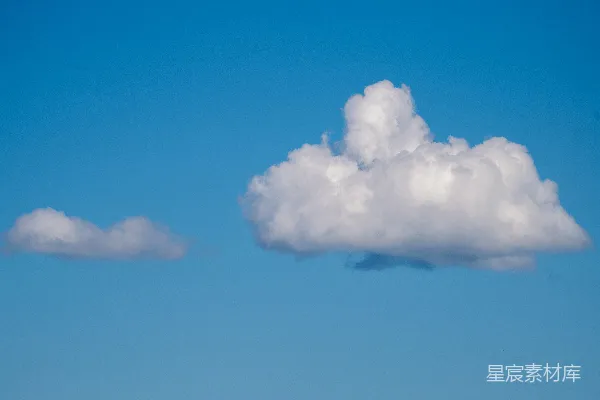 高清摄影 两只白色的绒球状云朵漂浮在一片湛蓝的天空中。