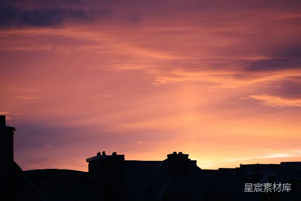 高清摄影 vibrant 粉红橙色的落日天空映衬着暗淡的屋顶。