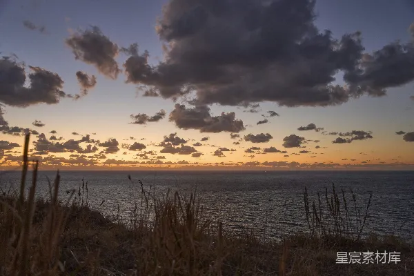 高清摄影 夕阳下的海洋，天空中有云朵。
