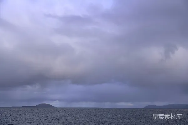 高清摄影 暗淡的云层笼罩着一片广阔的海洋，远处可见陆地。