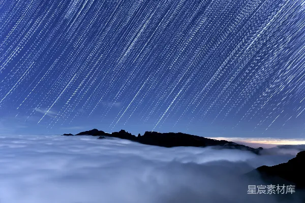 高清摄影 夜空中的星轨横跨云层和山峰之上。