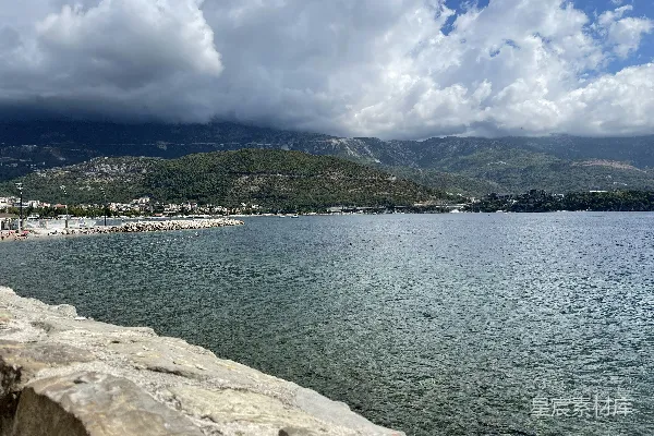 高清摄影 一片有岩石海岸的水域，背景中有山丘。