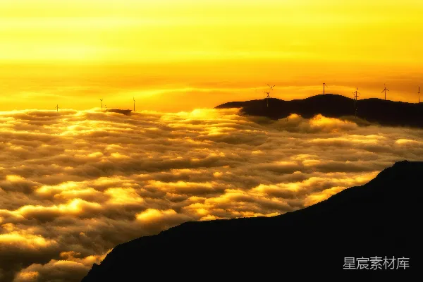 高清摄影 金色的夕阳映照在云层中，远处有风力涡轮机。