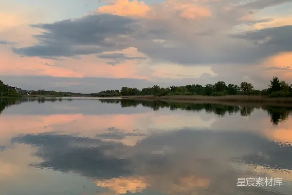 高清摄影 夕阳映照下，柔和的云彩倒映在平静的湖面上。