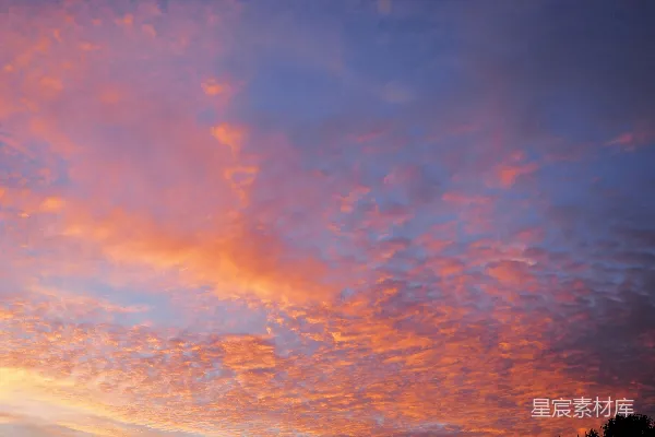 高清摄影 夕阳下，天空中飘浮着粉色和橙色的云朵。