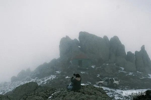 高清摄影 山顶上坐着一个人，脚下覆盖着积雪。