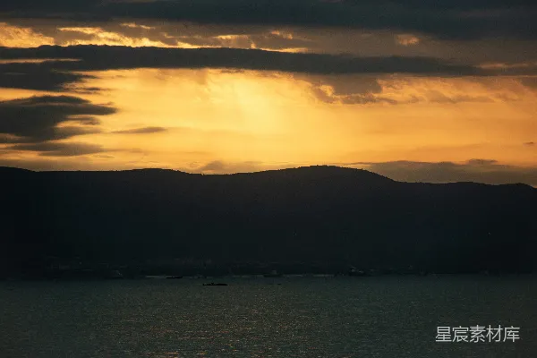 高清摄影 夕阳映照着黑暗的山峦和宁静的水面。