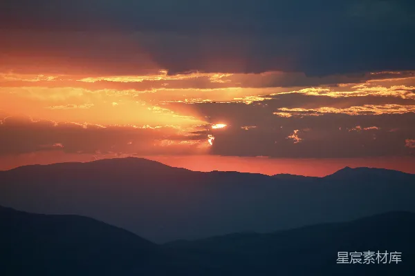 高清摄影 夕阳映照着轮廓分明的山峦群落，云彩显得格外 dramatic（戏剧性的）。