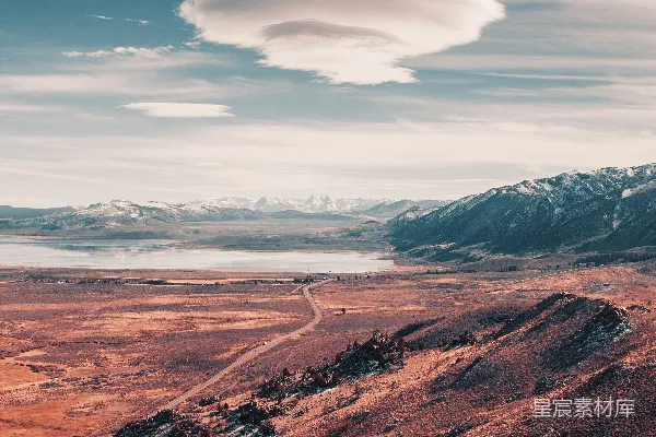 高清摄影 一段蜿蜒穿过沙漠的道路，在背景中是连绵的山峰。