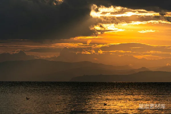 高清摄影 金黄的夕阳映照平静的大海，远处山峦隐约可见。