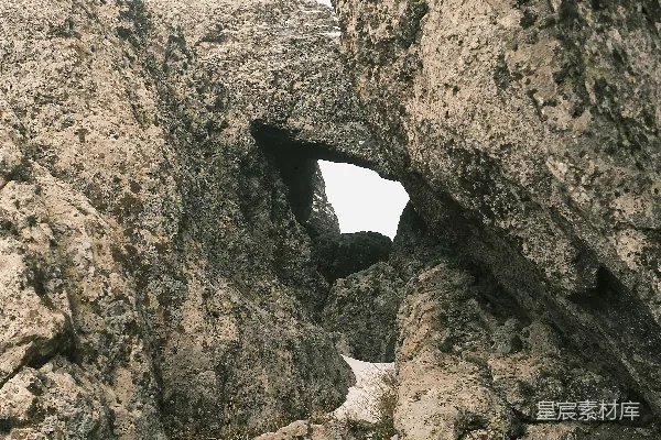 高清摄影 一个在岩石山丘上攀登的人，背景是天空。