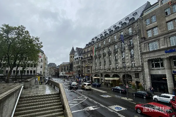 高清摄影 一辆红色的汽车沿着一条街道行驶，旁边是高大的建筑物。
