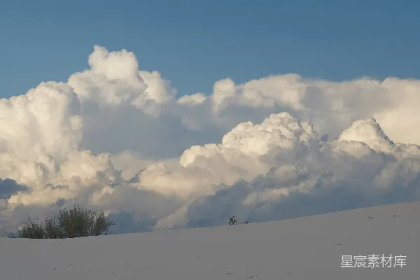 高清摄影 覆盖着白雪的山顶，背景是树木和云朵。