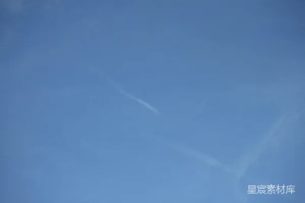 高清摄影 天空中飞行的飞机伴有长长的尾迹云。