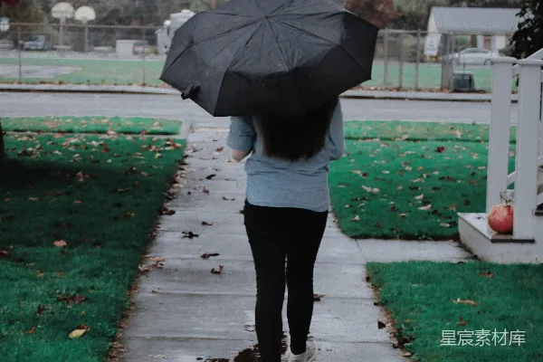 高清摄影 一个女人走在人行道上拿着雨伞