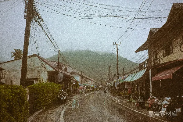 高清摄影 一条湿漉漉的街道，旁边停着一排摩托车。