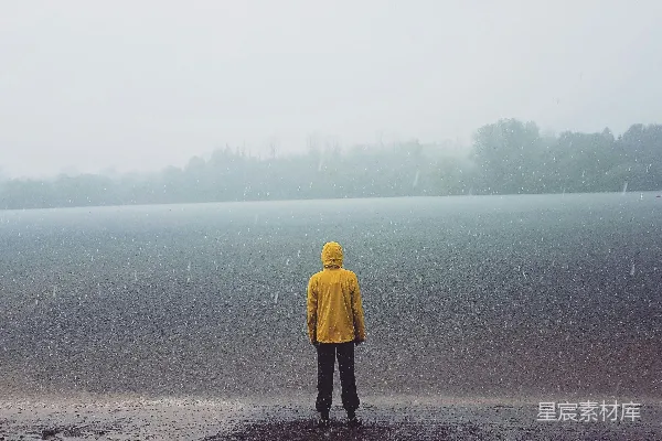 高清摄影 站在海边面对着海洋的男人正在雨中站立。
