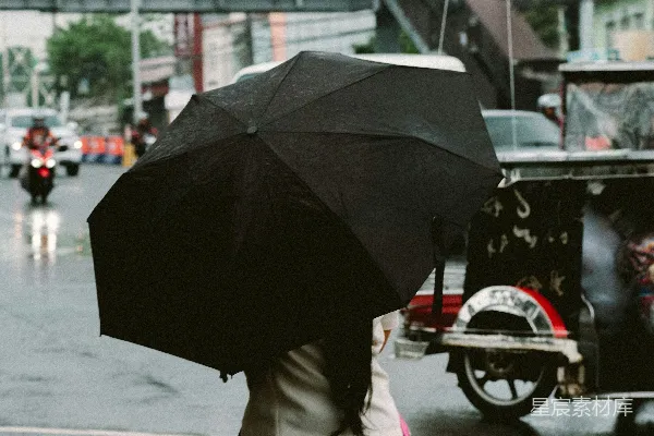高清摄影 一个男子走在街上拿着雨伞。