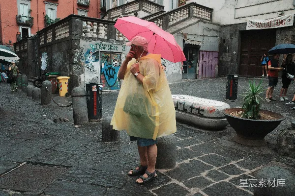 高清摄影 一个穿黄色雨衣的女人拿着一把粉红色的伞