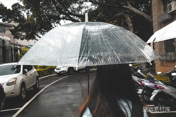 高清摄影 蓝色夹克的女子手持雨伞在街上行走，白天时段